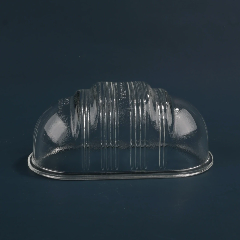 Clear oval lighting glass cover with central ribs and rounded ends on a dark background