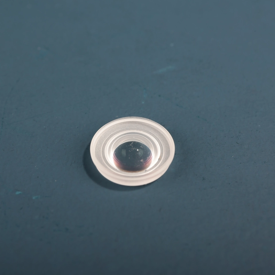 Small clear circular glass lens with a raised mounting rim on a blue background